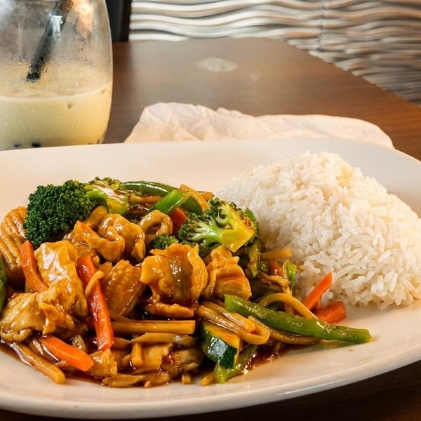 Chicken stir-fry with broccoli, carrots, and zucchini, served with white rice and a bubble tea.